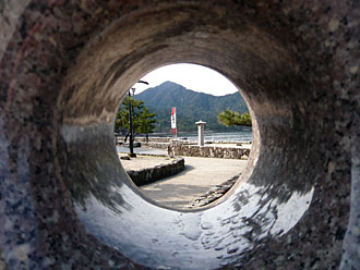 覗き穴から旗の隙間から宮島の厳島神社の大鳥居を見る